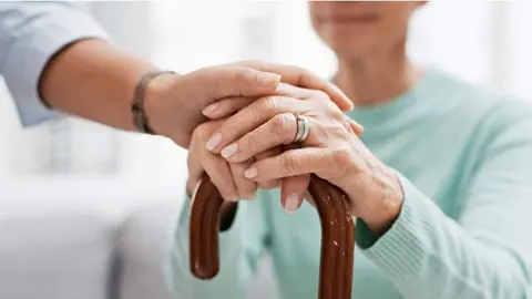 Una persona mayor con las manos apoyadas en un bast&oacute;n - Foto de la Comunidad de Madrid
