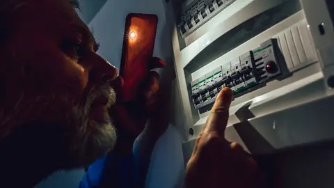 Un hombre mirando si puede volver a encender la luz | Foto de 123 rf/ jovanmandic