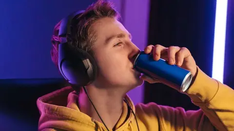 Gamer tomando una bebida energ&eacute;tica por la noche - Foto de Arsenii Palivoda de Getty Images