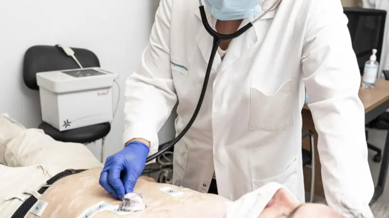 Un médico explorando a un paciente, ambos con mascarilla - Foto de Jorge Villa Bolaños/Servimedia