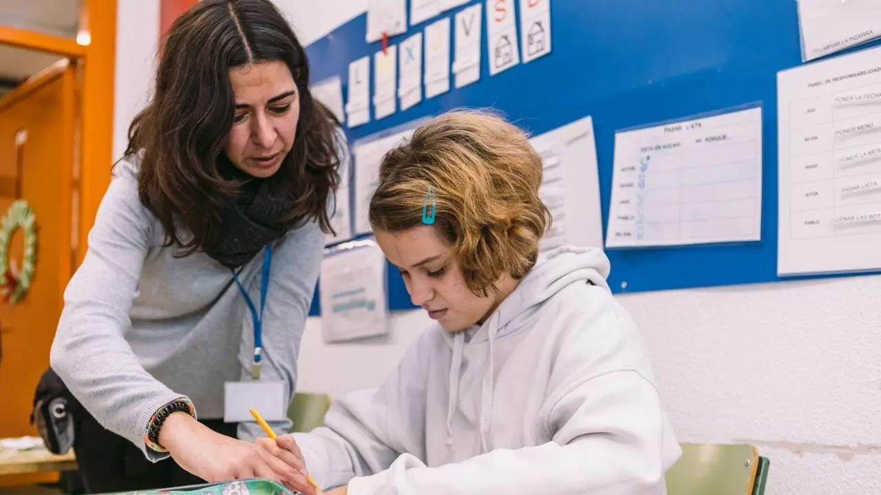 Una docente ayuda a una alumna con autismo - Imagen de Autismo España