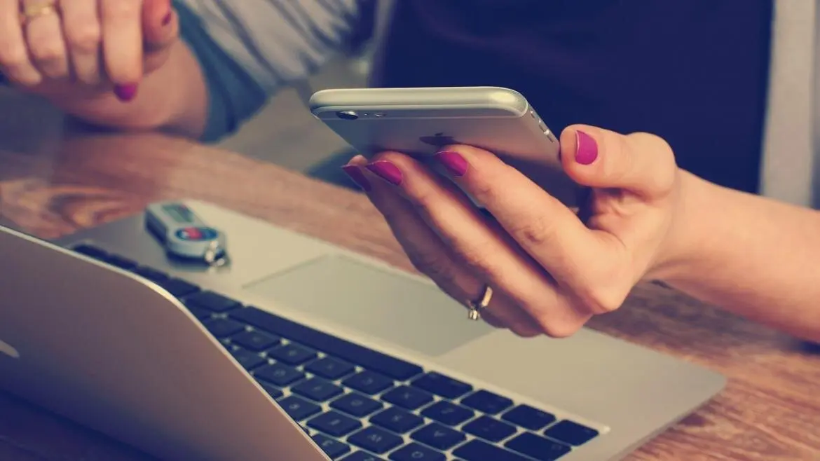 manos de mujer con portatil y movil