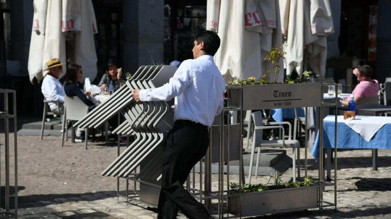 Imagen de archivo de un trabajador de hostelería colocando las sillas de una terraza de la Plaza Mayor de Madrid