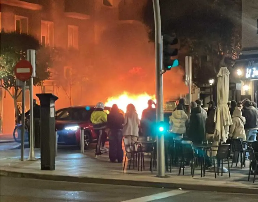 Un contenedor ardiendo en la calle Menorca con la calle Narv&aacute;ez - Foto Servimedia
