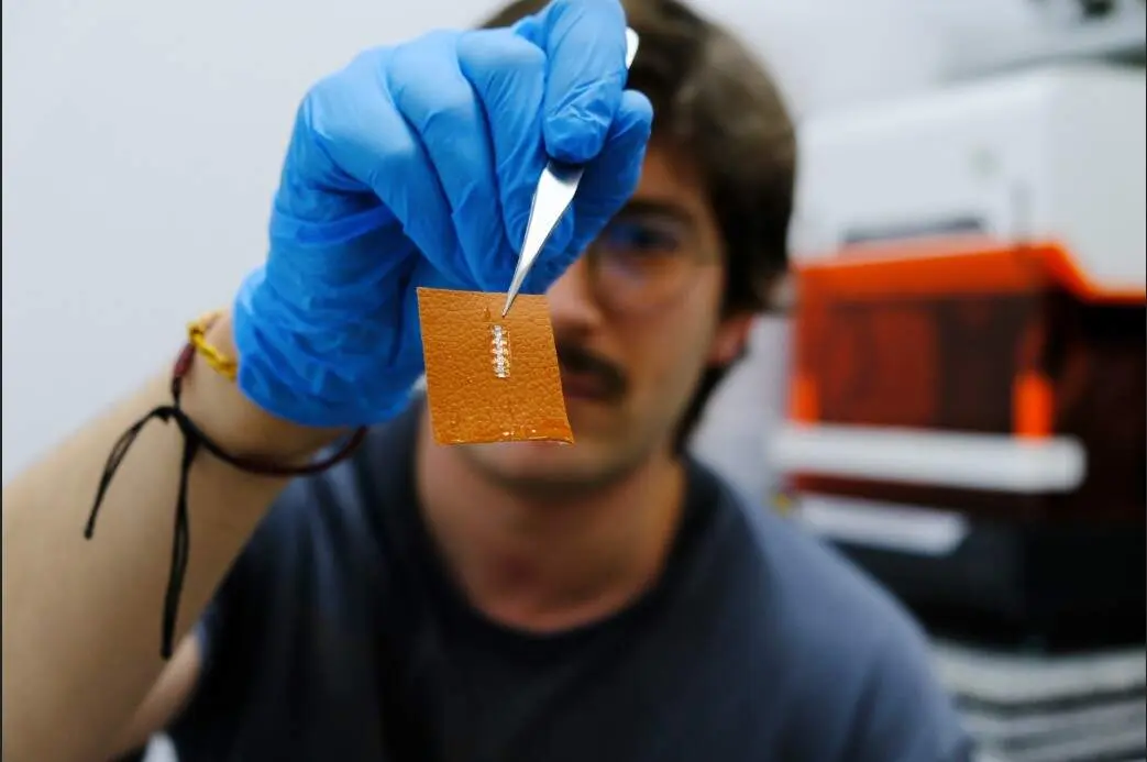 El investigador Yigit Sozen sostiene un chip en un trozo de piel./ &Aacute;ngela R. Bonachera. ICMM-CSIC.