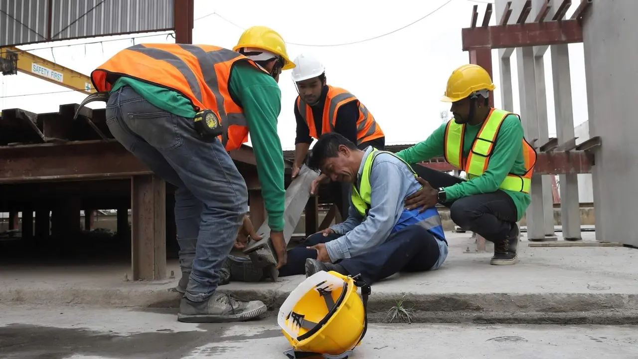Trabajadores ayudan a otro trabajador herido en un accidente laboral - Foto de mnbb de Getty Images