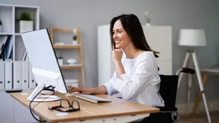 Mujer en silla de ruedas trabajando en un ordenador.