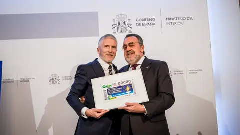 Fernando Grande-Marlaska y Miguel Carballeda sostienen una lámina enmarcada con este cupón - Servimedia