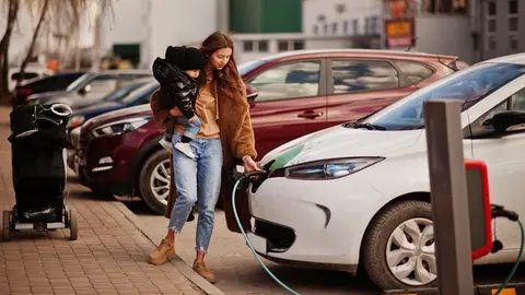 Conductora recargando su vehículo eléctrico | Foto de 123rf/asphoto77