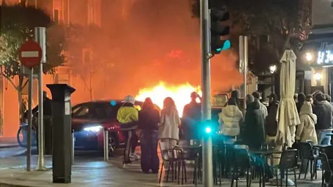 Un contenedor ardiendo en la calle Menorca con la calle Narv&aacute;ez - Foto Servimedia