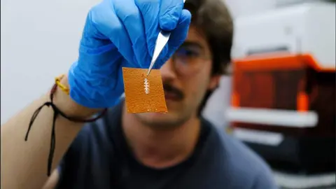 El investigador Yigit Sozen sostiene un chip en un trozo de piel./ &Aacute;ngela R. Bonachera. ICMM-CSIC.