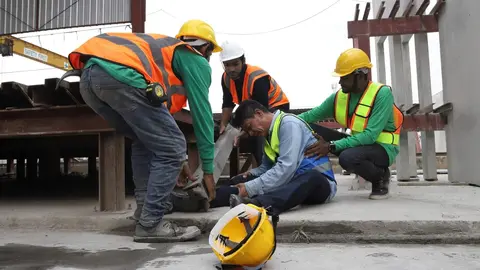 Trabajadores ayudan a otro trabajador herido en un accidente laboral - Foto de mnbb de Getty Images