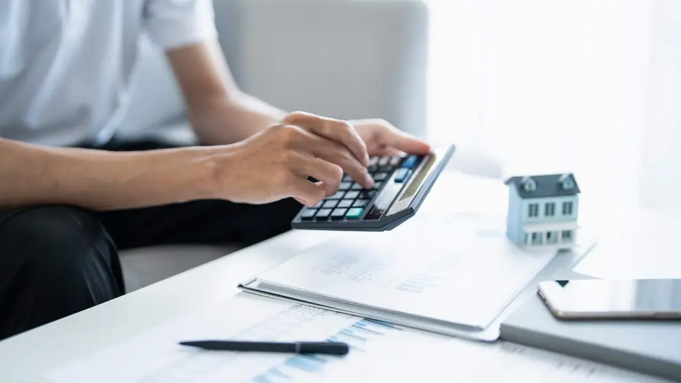 Hombre calcula las finanzas en casa: pago de facturas, impuestos, ahorros y econom&iacute;a - Foto de charliepix